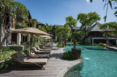 a row of chaise lounge chairs next to a swimming pool at Ramayana Suites and Resort in Kuta
