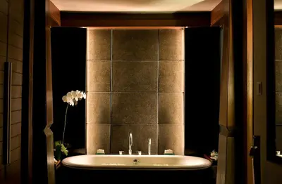 a bathroom with a bath tub with a mirror at The Kayana in Seminyak