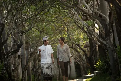 a man and a woman walking down a tree lined path at The Kayana in Seminyak
