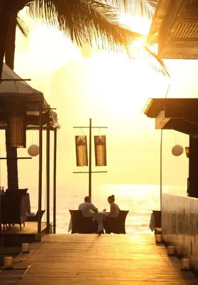 two people sitting at a table on the beach at The Samaya Seminyak Bali in Seminyak