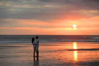 a couple standing on the beach at sunset at The Samaya Seminyak Bali in Seminyak