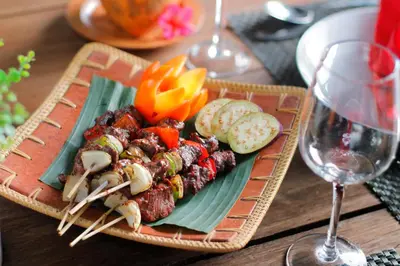 a plate of food with meat and vegetables on a table at Villa Suku Berawa in Canggu