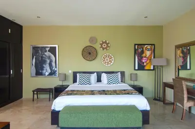 a bedroom with a large bed and some pictures on the wall at Villa Uma Sari - 2BDR, Private Pool and Sunset Rooftop, Quiet and Central in Seminyak