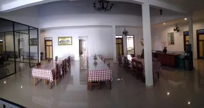 a dining room with tables and chairs and a kitchen at Rumah Retret Bethania in Kuta