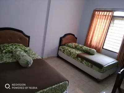 two beds sitting in a room with a window at Rumah Retret Bethania in Kuta