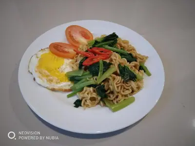 a plate of food with noodles and an egg and tomatoes at Rumah Retret Bethania in Kuta