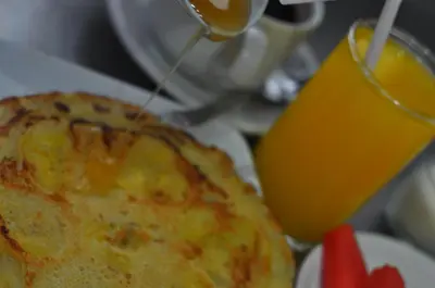 a table with a plate of food and a glass of orange juice at Jesens Inn II in Kuta