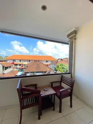 a balcony with a table and two chairs and a large window at Jesens Inn II in Kuta