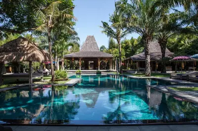 a swimming pool at a resort with palm trees at Blue Karma Village in Seminyak