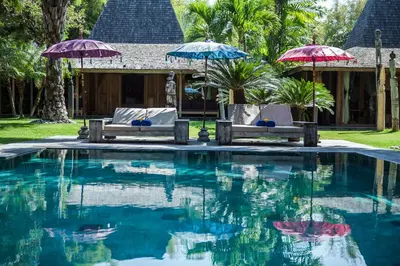 a swimming pool with two chairs and umbrellas at Blue Karma Village in Seminyak