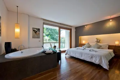 a bedroom with a large bed and a bath tub at VILLA OLYMPIA in Seminyak