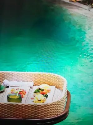 a table with food on it next to a swimming pool at VILLA OLYMPIA in Seminyak