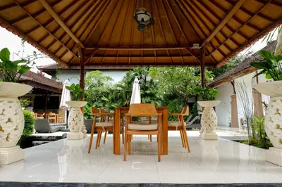 a dining room table and chairs under a wooden roof at Puri Panca Jaya Hotel in Seminyak