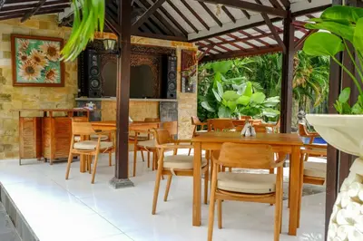 a dining room with wooden tables and chairs at Puri Panca Jaya Hotel in Seminyak
