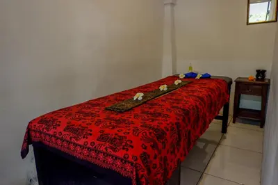 a red bed with a red comforter and a table at Puri Panca Jaya Hotel in Seminyak