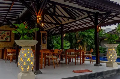a restaurant with tables and chairs under awning at Puri Panca Jaya Hotel in Seminyak