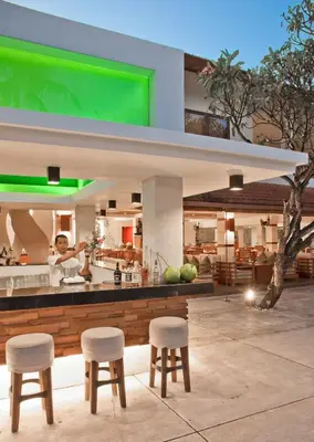 a restaurant with two stools and a counter with a kitchen at Bali Rani Hotel in Kuta