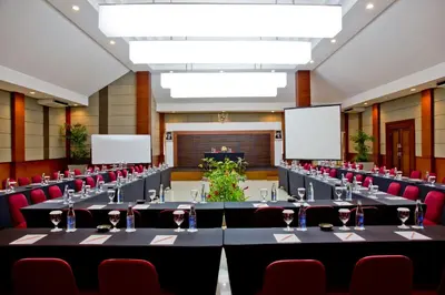 a conference room with tables and chairs and blank screens at Bali Rani Hotel in Kuta