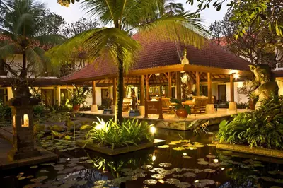 a villa with a pond in front of a house at Bali Rani Hotel in Kuta