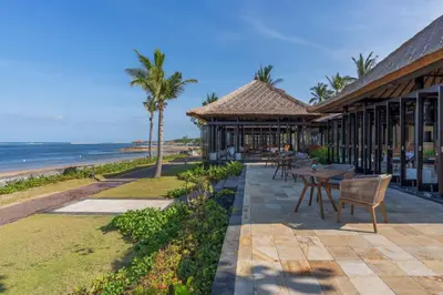 a resort with a table and chairs next to the beach at Conrad Bali in Nusa Dua