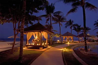 a resort with a gazebo and a pool at night at Conrad Bali in Nusa Dua