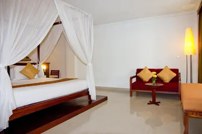 a bedroom with a canopy bed and a couch at The Rani Hotel & Spa in Kuta