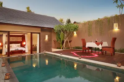 a pool with a table and a bed in a room at Lumbini Luxury Villas and Spa in Jimbaran