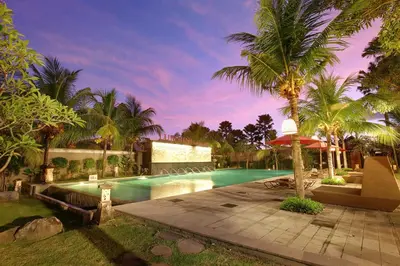 a swimming pool with palm trees and a house at Lumbini Luxury Villas and Spa in Jimbaran