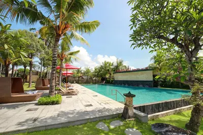 a swimming pool in a resort with palm trees at Lumbini Luxury Villas and Spa in Jimbaran