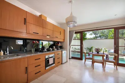 a kitchen with wooden cabinets and a table with chairs at Beautiful Bali Villas - 6 mins walk to the beach in Legian