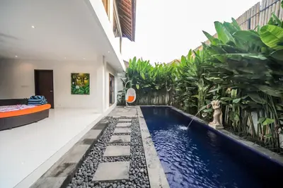 a swimming pool in the middle of a building with plants at Villa Pearl Seminyak in Seminyak