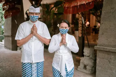 two people wearing face masks praying in a temple at Hotel Kumala Pantai in Legian