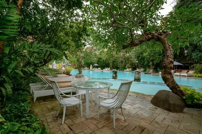a patio with a table and chairs next to a pool at Hotel Kumala Pantai in Legian