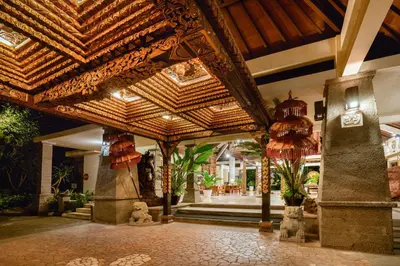 a resort lobby with a wooden ceiling with chandeliers at Hotel Kumala Pantai in Legian