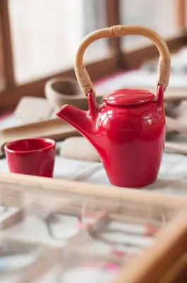 a red tea pot on a table with a red cup at Brown Feather Batu Belig in Seminyak