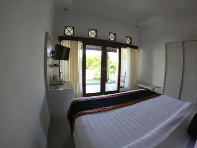 a bedroom with a large white bed with a window at Kaniya bali in Nusa Dua