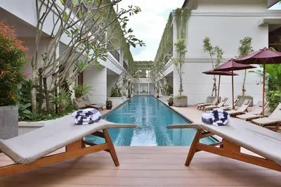 a pool in the middle of a building with chairs at Seminyak Lagoon All Suites Hotel in Seminyak