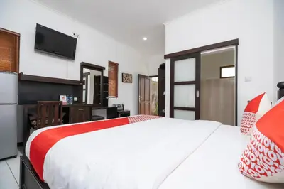 a bedroom with a large white bed and a television at Hotel O Panen House in Seminyak