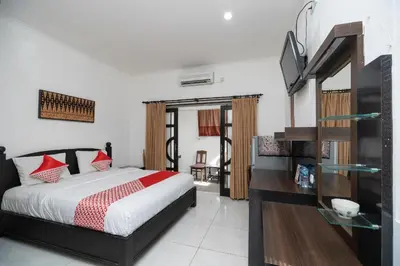 a bedroom with a bed and a television in it at Hotel O Panen House in Seminyak