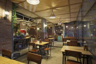 a restaurant with wooden tables and chairs and a brick wall at J Hotel Kuta in Kuta