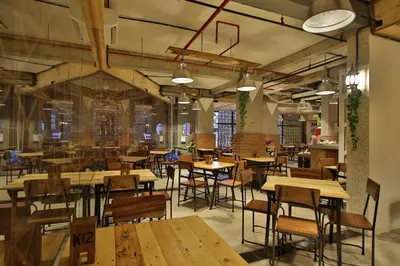 an empty restaurant with wooden tables and chairs at J Hotel Kuta in Kuta