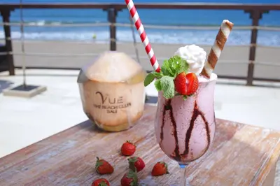 two milkshakes sitting on a wooden table with strawberries at Lv8 Resort Hotel in Canggu