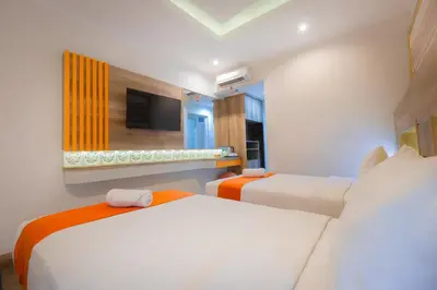 a bedroom with two beds and a tv on the wall at The Nyaman Hotel Bali in Kuta