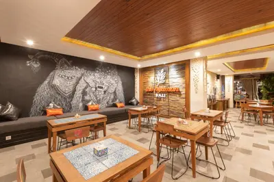 a restaurant with tables and chairs and a couch at The Nyaman Hotel Bali in Kuta
