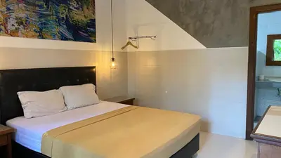 a bedroom with a bed and a painting on the wall at Sandat Hotel Legian in Legian