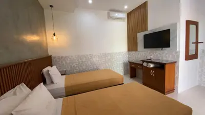 a hotel room with two beds and a television at Sandat Hotel Legian in Legian