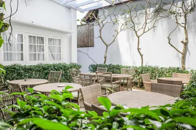 an outdoor patio with tables and chairs and trees at Umalas Suites in Seminyak