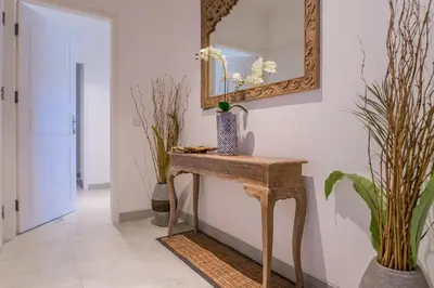 a console table in a hallway with a mirror and plants at Umalas Suites in Seminyak