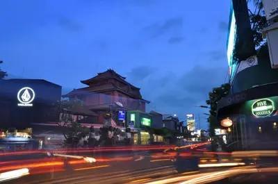a busy city street at night with cars at Bemo Corner Guest House in Kuta