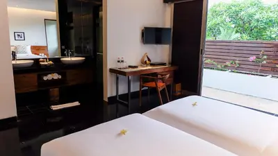 a bedroom with two beds and a bathroom with a sink at Sun Island Boutique Villas & Spa Seminyak in Seminyak